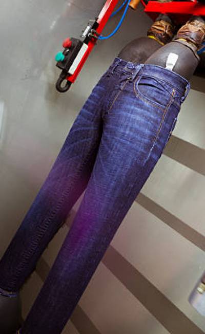 Jeans pants getting spray paints in Eco-Friendly Professional Spray and Chemical Application Cabinets for special effects on jeans in denim manufacturing factory.